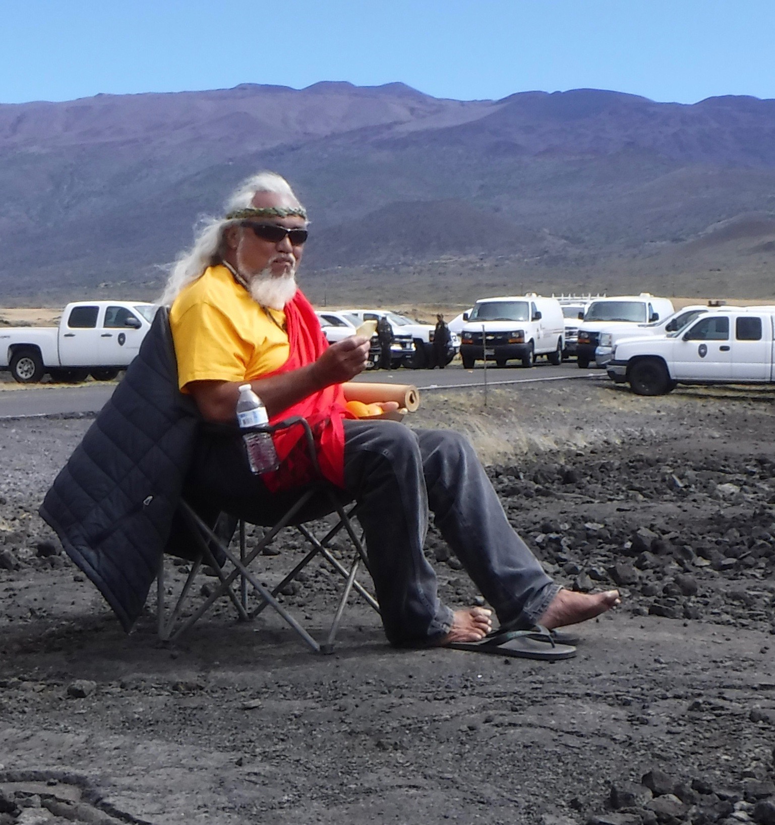 Man sitting in chair with trucks and vans in the background