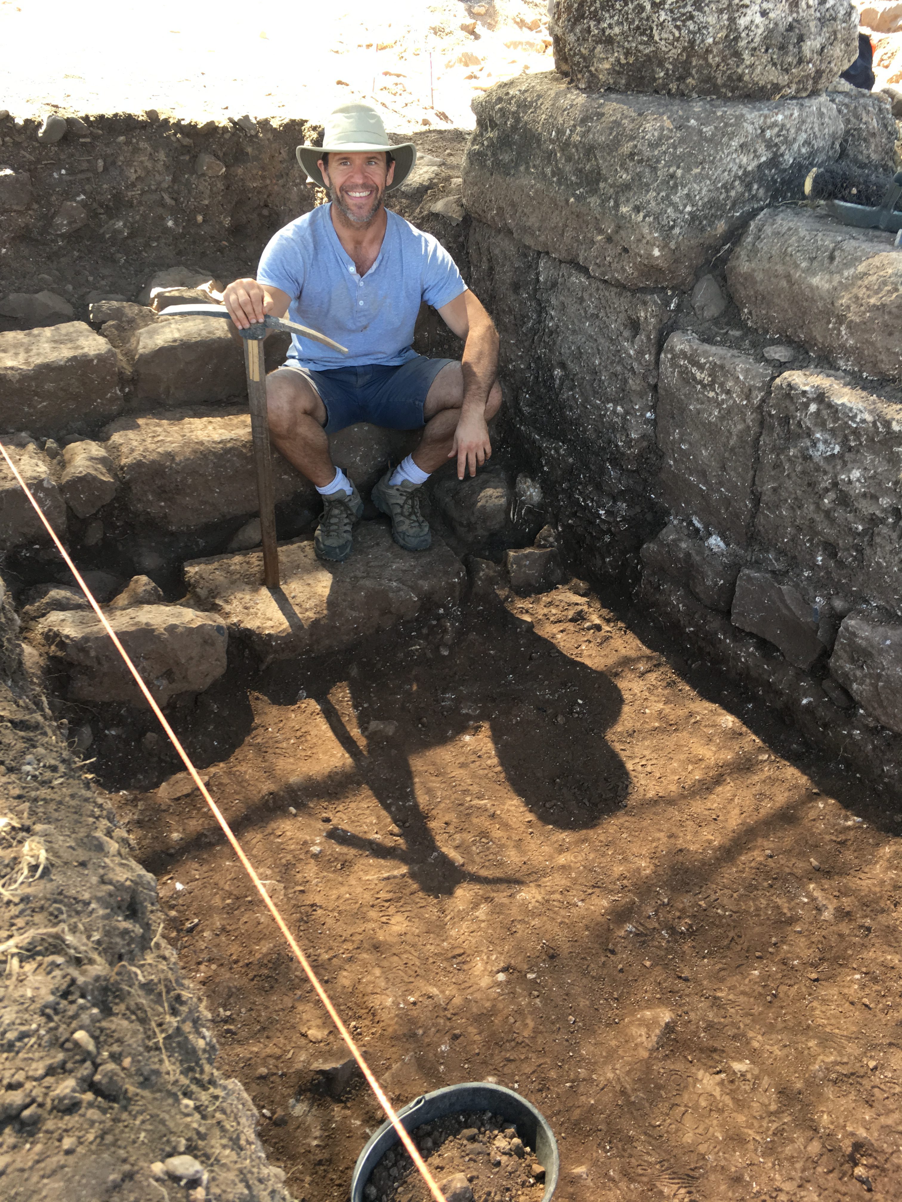 Marshall Evans in ruins holding a pick axe and with a hard helmet