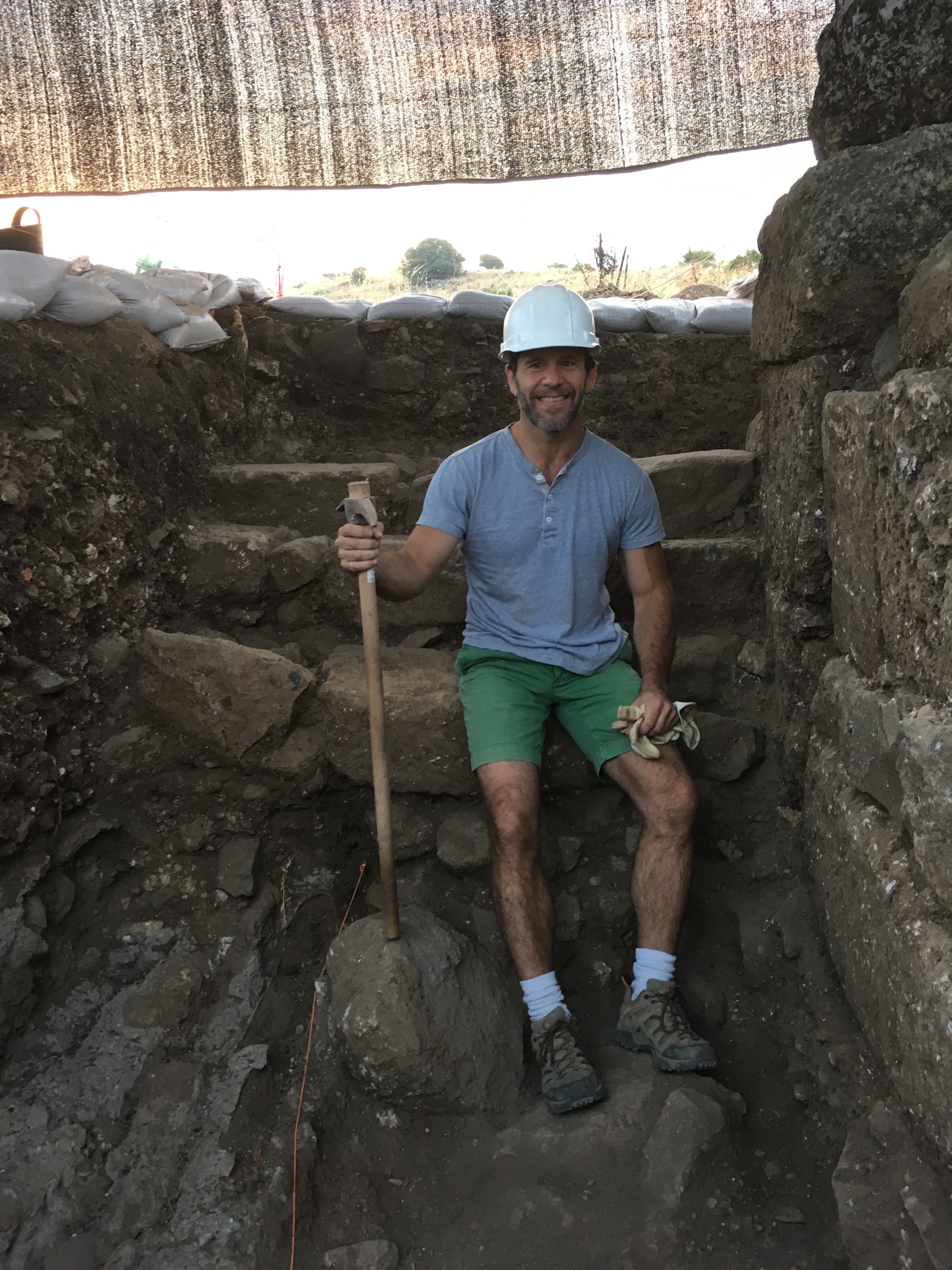 Marshall Evans in ruins holding a pick axe and with a hard helmet