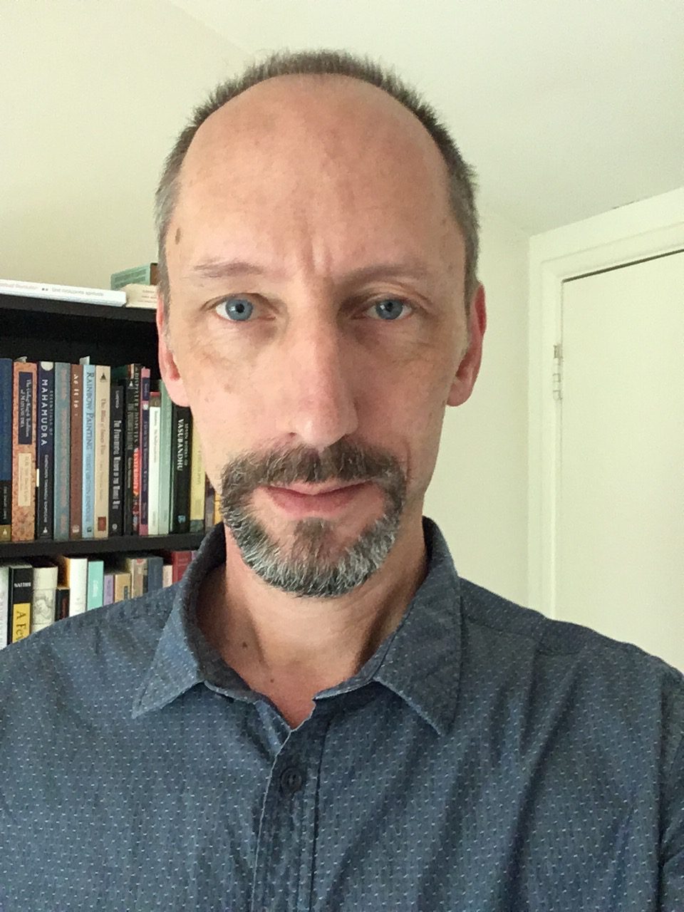 Patrick Lambelet headshot in front of bookcase filled with books