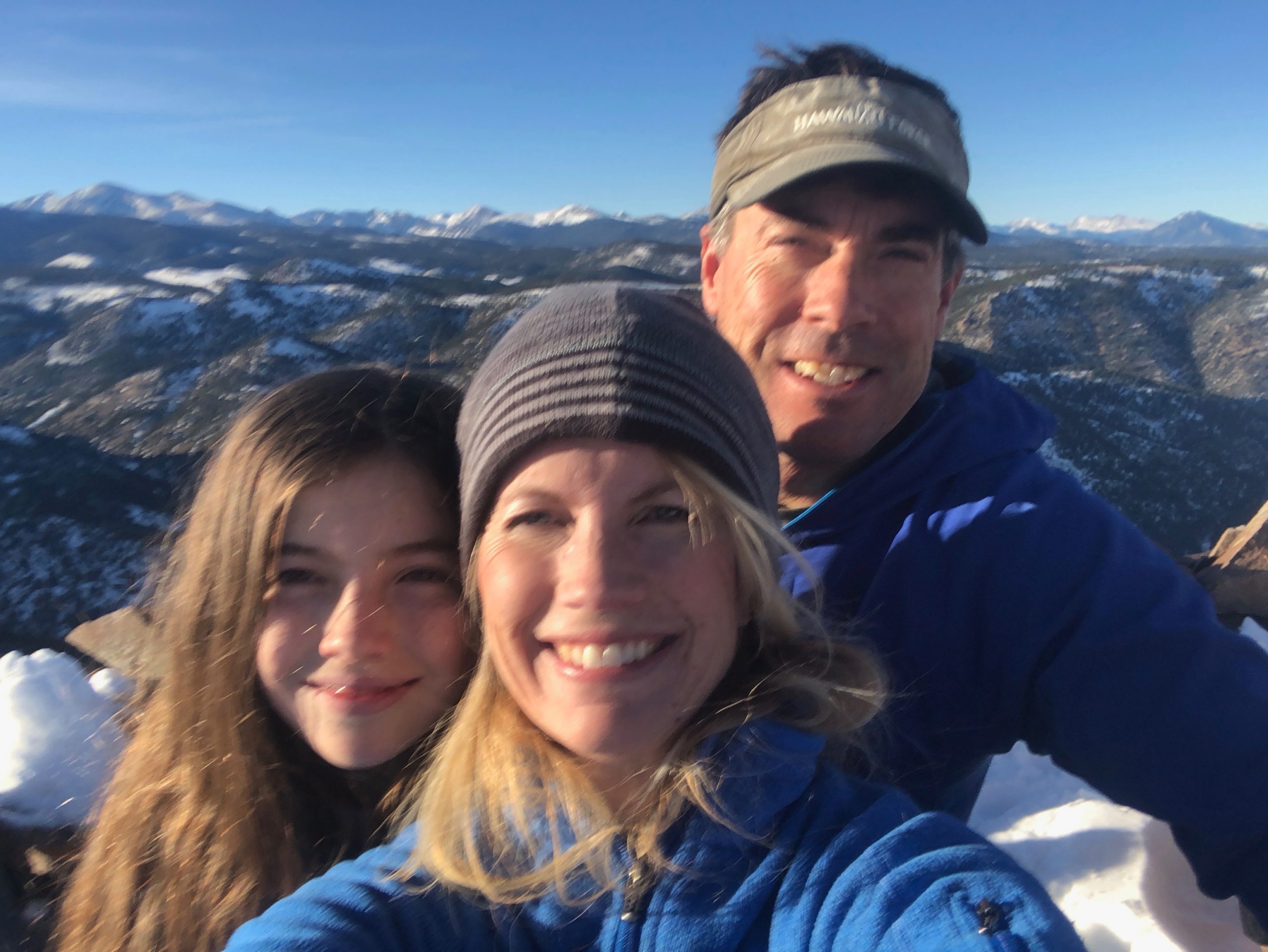 Man, women, and teen girl in selfie style image with mountains in the background